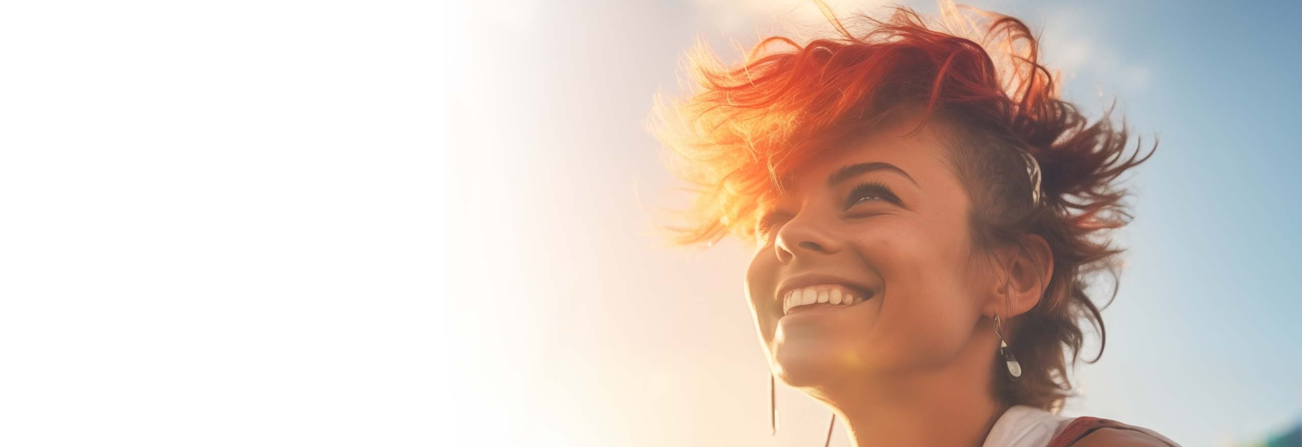 Junge, glückliche lesbische Frau mit leuchtend orangerotem Haar lächelt stolz beim Feiern des LGBTQ-Festivals „Gay Pride“ in der Abendsonne.