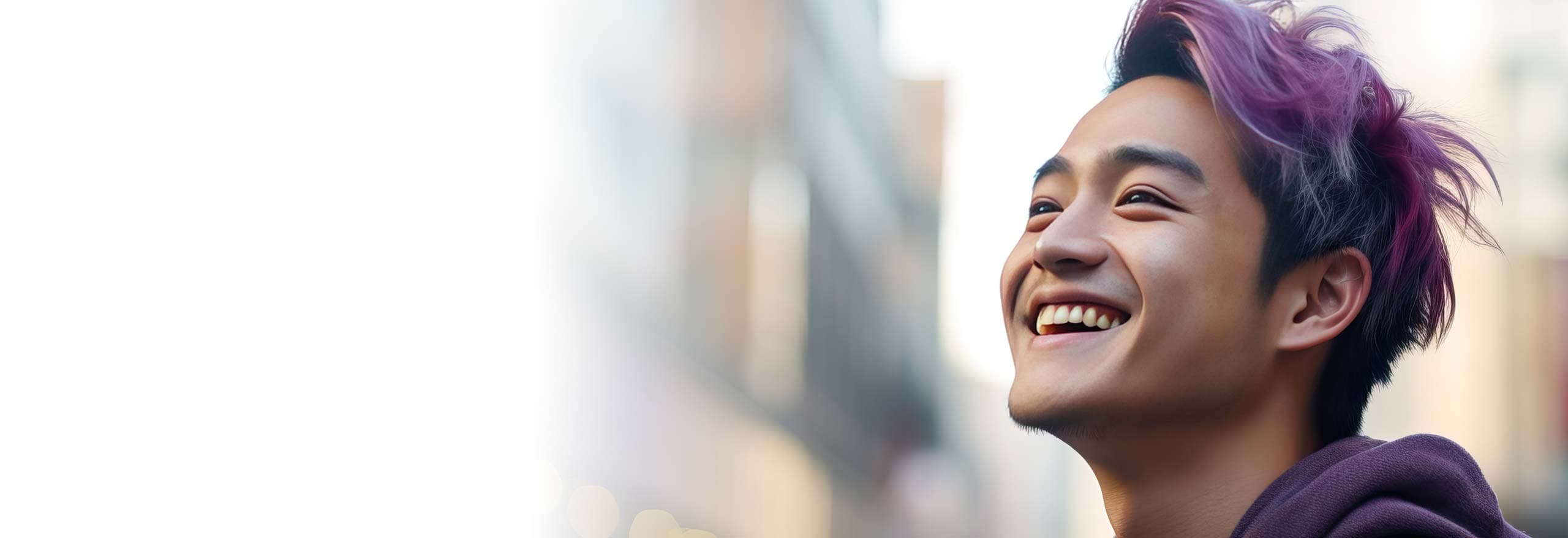 Lächelnder junger Mann mit lilafarbenen Haarsträhnen blickt nach oben; im Hintergrund verschwommene Stadtlichter.